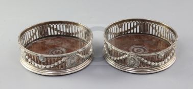 A pair of George III silver wine coasters, by J.E. Terrey & Co, the pierced bodies decorated with