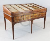 A George III mahogany display table, with slanted glazed two door top and eight frieze drawers, on