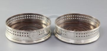A pair of George III pierced silver wine coasters, with engraved decoration and turned wooden bases,