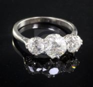 A mid 20th century platinum and three stone diamond ring, the central round cut stone weighing