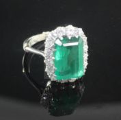 A platinum, emerald and diamond cluster ring, the emerald cut stone measuring 12.9mm by 8.9mm by 5.