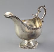 A George III silver sauceboat, London, 1767, with gadrooned border and engraved crest, on cast