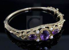 A 1970's Victorian style 9ct gold, amethyst and seed pearl set hinged bangle.