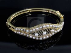 A gold and seed pearl set hinged bangle, with central trellis motif.