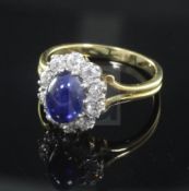 A cabochon sapphire and diamond cluster ring, the central sapphire surrounded by 10 brilliants, on