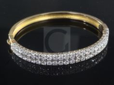 A gold and double row channel set diamond hinged bangle, set with fifty two round cut stones with