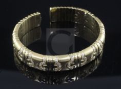 An 18ct gold and diamond open bangle, with diamond set semi-circular motifs.