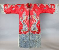 A Chinese embroidered silk 'dragon' robe, woven in metal thread and long threads on a red satin