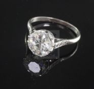 A platinum and single stone diamond ring with diamond set shoulders, the round cut stone with an