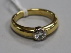 A modern 18ct gold and solitaire collet set diamond ring, size O.