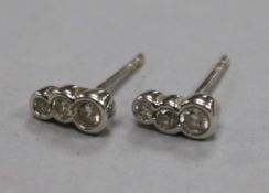 A pair of 18ct white gold and collet set graduated three stone diamond earstuds, approx. 7mm.From