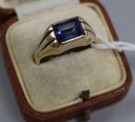 A yellow metal and synthetic blue sapphire dress ring with fluted shoulders, size S.