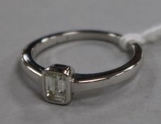 A modern 18ct white gold and solitaire baguette cut diamond ring, size M.