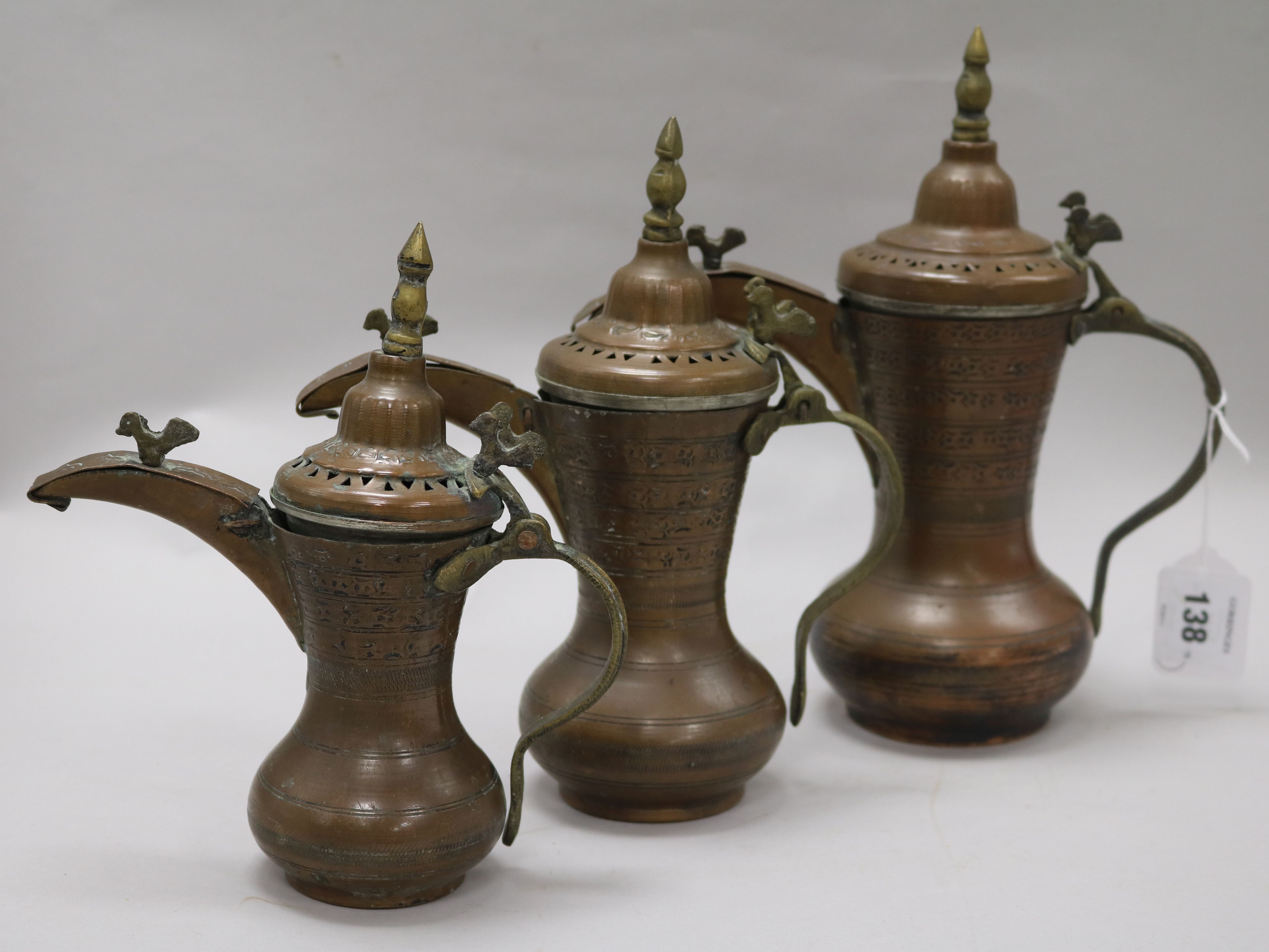 A set of three Bahrain brass and copper dallah coffee pots with old receipt from 1984 largest 28cm