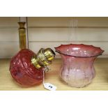 A cranberry glass oil lamp and shade on brass column