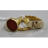 A 22ct gold wedding band and two yellow metal rings including one set with carnelian stone.