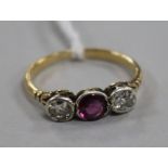 An early 20th century yellow metal and three stone diamond and garnet ring, size M.
