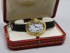 A lady's 18ct gold Cartier oval cased wrist watch, with Cartier box.