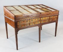 A George III mahogany display table, with slanted glazed two door top and eight frieze drawers, on