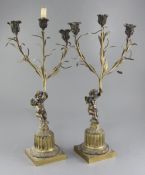 A pair of 19th century French bronze candelabra, modelled with cherubs holding aloft lilies, 23in.