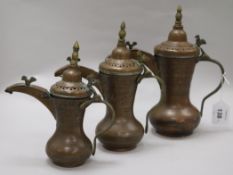 A set of three Bahrain brass and copper dallah coffee pots with old receipt from 1984 largest 28cm