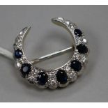 A modern 18ct gold, sapphire and diamond set crescent brooch, 28mm.