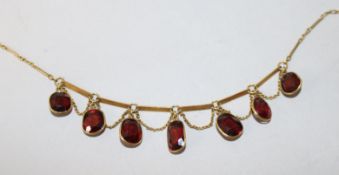 A yellow metal and garnet set necklace, 40cm.