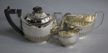 A matched three-piece silver batchelor tea service, of oval half-fluted form, comprising teapot