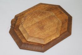 A Robert 'Mouseman' Thompson octagonal bread board with signature mouse and a similar pot stand W