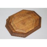 A Robert 'Mouseman' Thompson octagonal bread board with signature mouse and a similar pot stand W