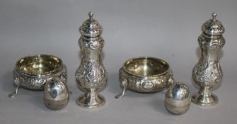 A pair of Victorian silver pepperettes, a pair of silver bun salts and two egg shaped pepperettes.