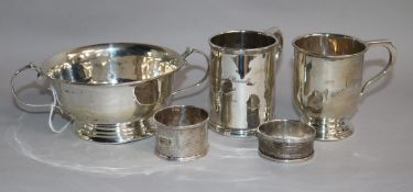 A George V silver two handled porringer, two silver christening mugs and two silver napkin rings.