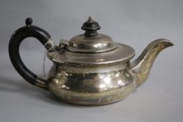 A 1920's small silver teapot, of squat circular form, with ebonised handle and finial, gross 14.5
