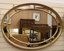 A gilt-framed oval wall mirror with marginal plates W.122cm