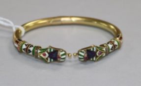 An Egyptianesque yellow metal, enamel and gem set hinged bangle.