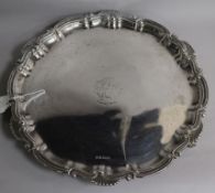 A silver salver with scroll and shell edge on three claw and ball feet, monogrammed, 37.5cm