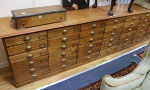 A late Victorian pine bank of forty two drawers, with brass "cup" handles, under a one piece