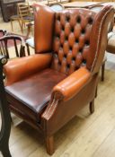 A tan leather buttonback armchair
