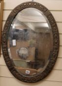 An embossed copper oval mirror W.49cm