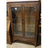 A carved oak two door glazed leaded cabinet W.81cm