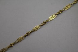 A yellow metal filigree bracelet, composed of pierced long oval links with chain-link spacers (tests