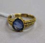 A yellow metal and shaped cut blue sapphire ring, the shank with beaded decoration (tests as 22ct