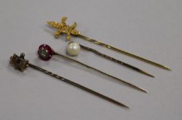 A Victorian ruby and diamond stick pin and three other stick pins, one with fleur-de-lys terminal