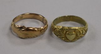 A yellow metal fede ring and another yellow metal ring with carved heart and foliate motifs (test as