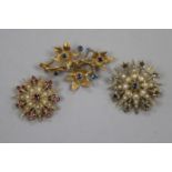 Two 9ct gold and gem set starburst brooches and a 9ct gold and gem set floral spray brooch,