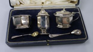 A cased silver three piece condiment set and two silver condiment spoons.