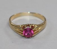 An 18ct gold and synthetic ruby ring, the circular cut stone set between channel-set shoulders, size