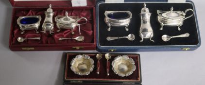 Two cased modern silver three piece condiment sets and a cased pair of Victorian silver salts and