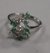 An 18ct white gold emerald and diamond cluster dress ring, size L.
