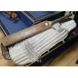 A leather cricket bag, pads and a bat